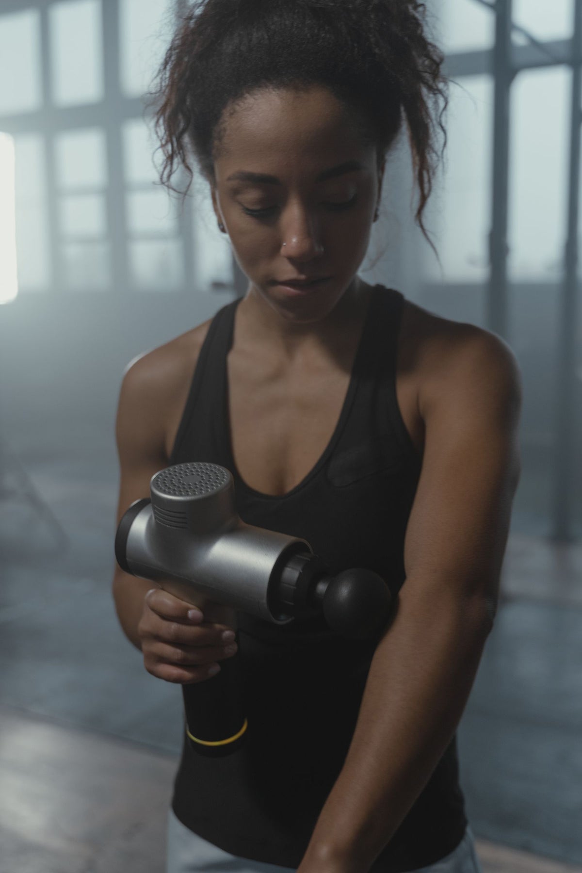 Percussion massage gun being used on a shoulder