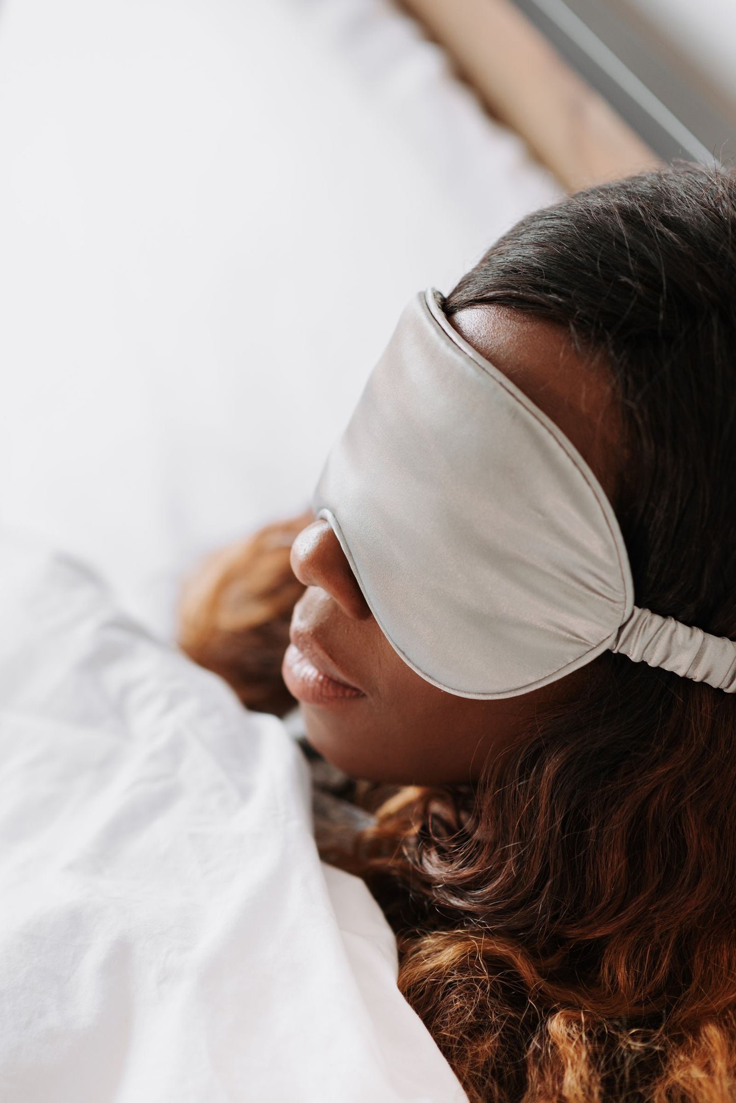 Woman resting in bed wearing a sleep mask